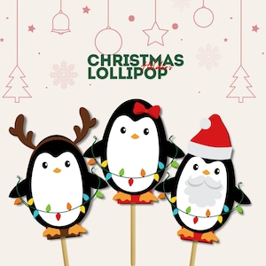 May include: Three penguin lollipop holders on wooden sticks. The left penguin wears reindeer antlers, the center penguin has a red bow, and the right penguin wears a Santa hat and beard. Each holds a string of colorful Christmas lights.