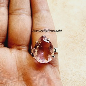 May include: A pear-shaped amethyst ring set in sterling silver. The ring features a large, faceted amethyst gemstone with a deep purple hue.