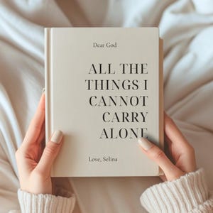 Może przedstawiać: Kremowa książka w twardej oprawie z czarnym tekstem na okładce o treści: Dear God, ALL THE THINGS I CANNOT CARRY ALONE, Love, Selina. Książka jest trzymana pionowo, wyraźnie prezentując tytuł oraz imię autorki na jasnym tle.
