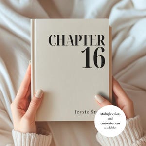 Puede incluir: Un libro de tapa dura con cubierta color crema que presenta el texto negro CHAPTER 16 impreso en una fuente serif grande en la parte superior y el nombre Jessie Sm en una fuente más pequeña en la parte inferior, sostenido sobre un fondo de tela suave.