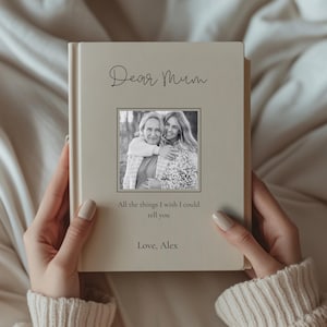 May include: A beige hardback book with the text "Dear Mum" in cursive. A black and white photo of two women is centered below the text. The text "All the things I wish I could tell you" and "Love, Alex" are below the photo.