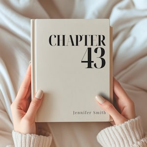 Puede incluir: Un libro de tapa dura con una cubierta de color crema que presenta el texto negro CHAPTER 43 en la parte superior y el nombre Jennifer Smith impreso en una fuente más pequeña en la parte inferior. El libro se sostiene verticalmente.