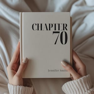 May include: A cream-coloured hardcover book with the title "CHAPTER 70" in large, black letters. The author's name, Jennifer Smith, is printed at the bottom. The book is held by a person wearing a cream-coloured sweater.