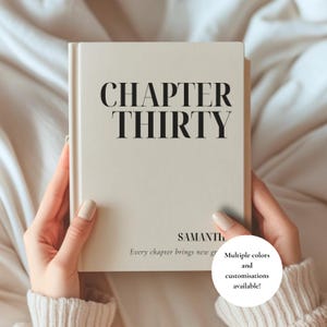 Puede incluir: Un libro de tapa dura de color crema con el texto negro CHAPTER THIRTY impreso en una fuente serif. Debajo, el nombre SAMANTHA está impreso, seguido del texto Every chapter brings new growth. Un gráfico circular blanco indica Multiple colors and customisations available!