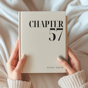 Puede incluir: Un libro de tapa dura con cubierta de color crema que presenta el texto negro CHAPTER 57 en una fuente serif grande en la parte superior y el nombre Jessie Smith en una fuente más pequeña en la esquina inferior derecha, sostenido por dos manos.