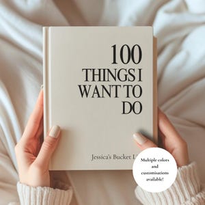 May include: A cream-colored hardcover journal with black text on the front cover that reads 100 THINGS I WANT TO DO and Jessica's Bucket List. The journal has a clean, minimalist design with a smooth finish and a sturdy spine, presented clearly.