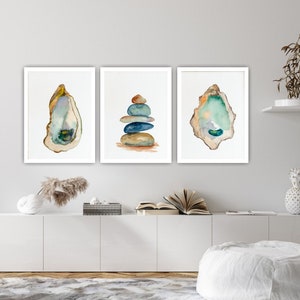 Peut inclure: Trois aquarelles encadrées sur un mur blanc. Les peintures représentent une pile de pierres bleues et brunes, une seule coquille d'huître et une seule coquille d'huître avec un intérieur vert.