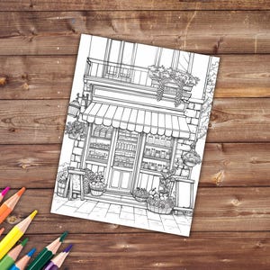 May include: A black and white line drawing of a storefront with a striped awning. The storefront has a window display with shelves of goods and a door. There are plants and baskets of fruit outside the store.