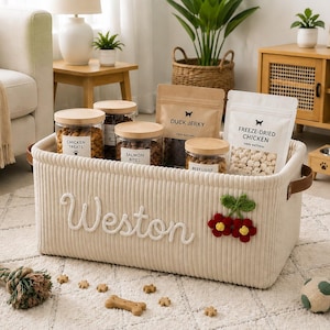 Peut inclure: Un panier de rangement rectangulaire en velours c&ocirc;tel&eacute; cr&egrave;me avec le nom Weston brod&eacute; en &eacute;criture blanche et une applique cerise rouge et verte. Le panier poss&egrave;de des poign&eacute;es lat&eacute;rales en similicuir marron et contient des friandises.