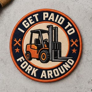 May include: A circular embroidered patch featuring an orange forklift in the center on a beige background. The border is dark blue with orange trim, displaying the text I GET PAID TO FORK AROUND in white, accented by two orange wrenches and stars.