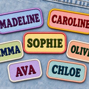 Puede incluir: Siete parches rectangulares bordados con esquinas redondeadas. Los parches muestran los nombres MADELINE, CAROLINE, SOPHIE, EMMA, OLIVIA, AVA y CHLOE en hilos de varios colores sobre fondos pastel contrastantes con bordes a juego.