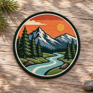 Puede incluir: Un parche bordado circular que muestra un paisaje con montañas nevadas, un río azul serpenteante y pinos verdes bajo un cielo naranja con un sol amarillo. El diseño está encerrado por un borde verde oscuro con costuras visibles.