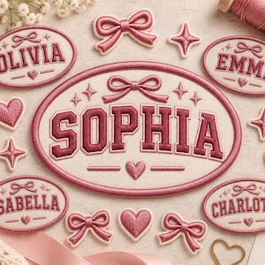May include: A collection of embroidered patches featuring oval name tags with the names Olivia, Emma, Sophia, Isabella, and Charlotte in dark pink thread on a cream background, accented with pink bows, hearts, and four-pointed star shapes.