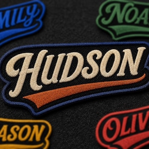 Puede incluir: Un parche bordado negro con el nombre HUDSON en letras cursivas de color beige, un borde azul y un subrayado naranja. Otros parches con los nombres EMILY, NOAH, MASON y OLIVIA son visibles en las esquinas de la imagen.