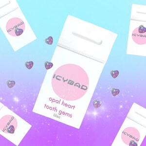 May include: A small white bag with a pink circle containing the text "ICYBAD" in silver glitter. The bag has a hole at the top for hanging. The text "opal heart tooth gems lilac" is printed below the circle.