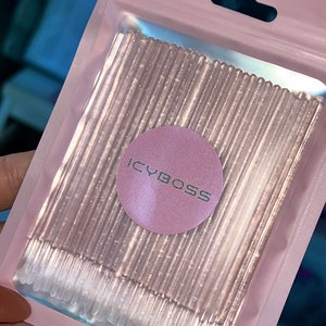 Könnte beinhalten: Eine rosa Plastikverpackung mit zahlreichen transparenten, glitzernden Applikatoren. Die Verpackung hat ein rundes Etikett mit dem silbernen Text "ICYBOSS". Die Applikatoren sind ordentlich angeordnet, wahrscheinlich für kosmetische oder Schönheitszwecke.