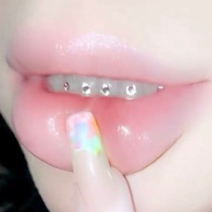 Pastel lips with tooth gems showing on bottom row of teeth