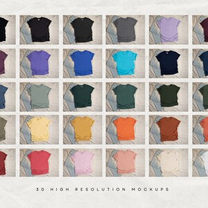 May include: Thirty high-resolution mockups of t-shirts in various colors, including black, purple, blue, green, yellow, orange, red, pink, and white. The shirts are laid out on a textured surface with a denim background.