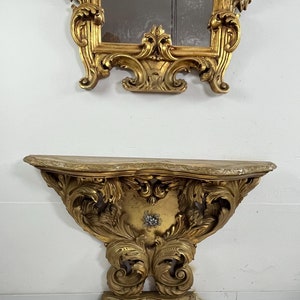 Könnte beinhalten: Ein vergoldeter, verzierter, wandmontierter Konsolentisch mit einer Marmorplatte. Der Tisch verfügt über aufwendige Schnitzereien und ein geschwungenes Design.
