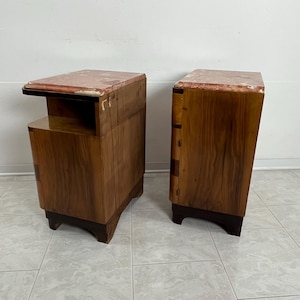 May include: A pair of wooden nightstands with marble tops. The nightstands have a dark wood finish and a curved design. Each nightstand has a drawer and a shelf.