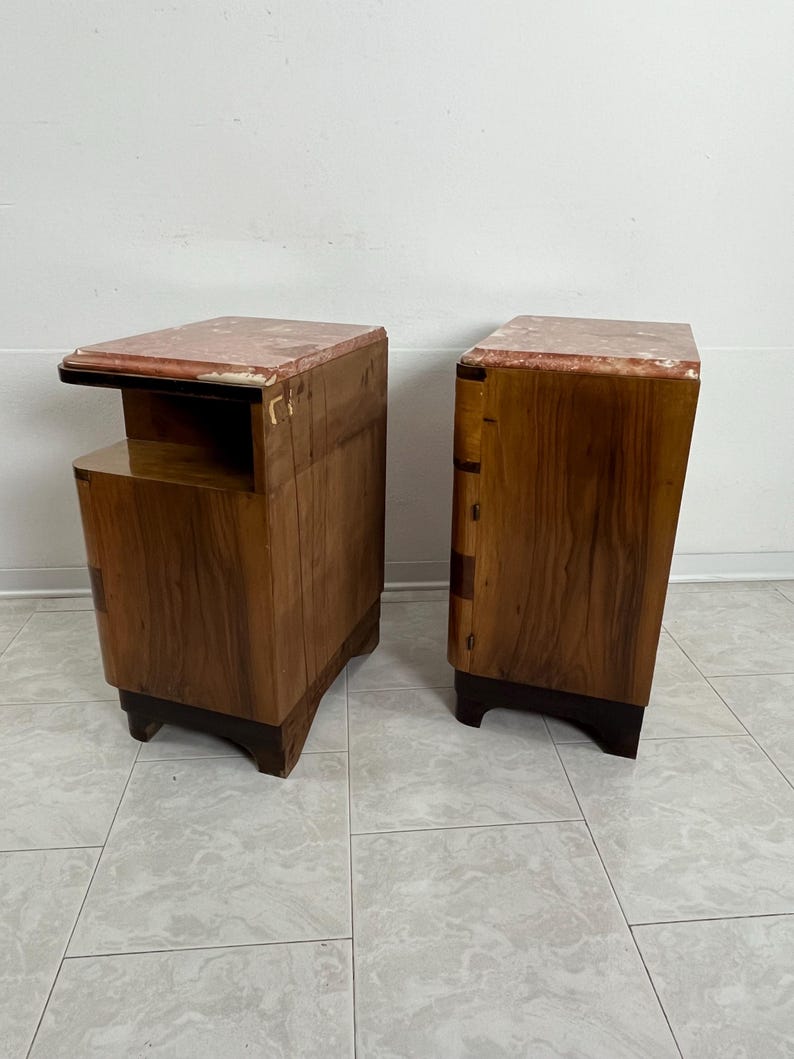 May include: A pair of wooden nightstands with marble tops. The nightstands have a dark wood finish and a curved design. Each nightstand has a drawer and a shelf.