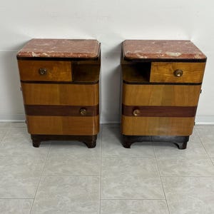 May include: A pair of vintage wooden nightstands with marble tops. Each nightstand has a drawer and a shelf. The nightstands are in good condition and have a beautiful patina.