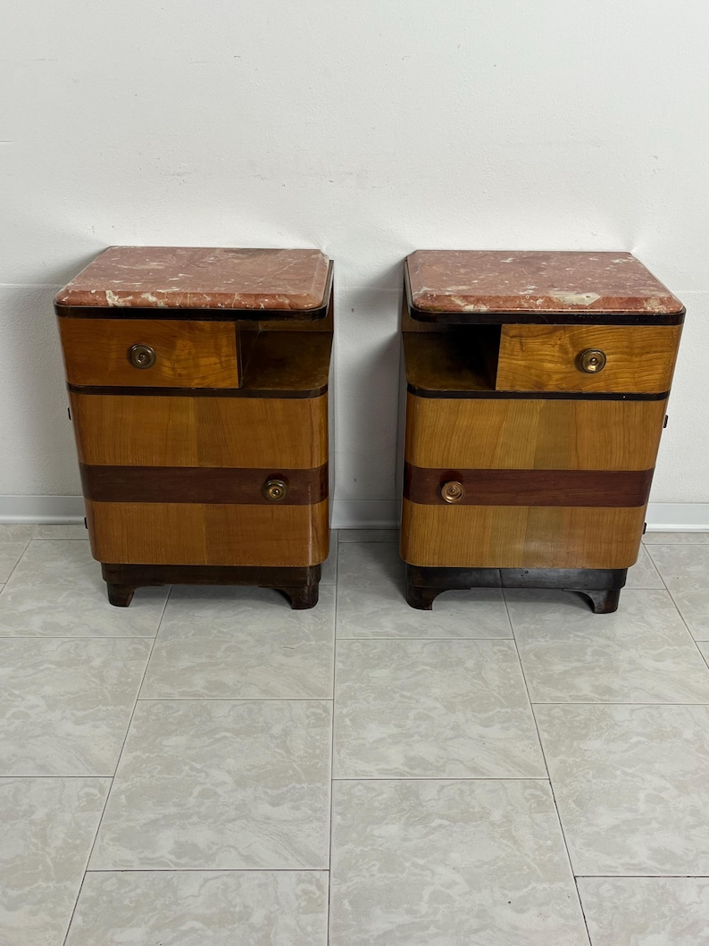 May include: A pair of vintage wooden nightstands with marble tops. Each nightstand has a drawer and a shelf. The nightstands are in good condition and have a beautiful patina.