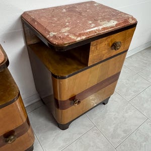 May include: A pair of vintage bedside tables with a wood veneer finish and a pink marble top. Each table has two drawers and a small shelf.