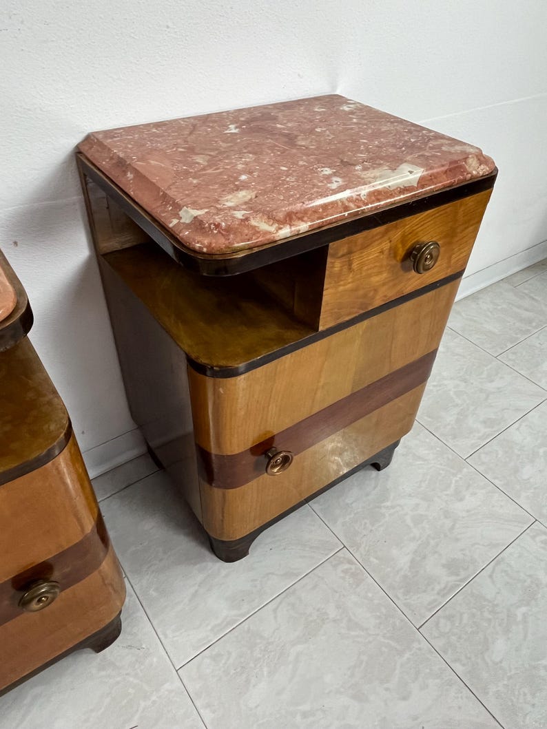 May include: A pair of vintage bedside tables with a wood veneer finish and a pink marble top. Each table has two drawers and a small shelf.
