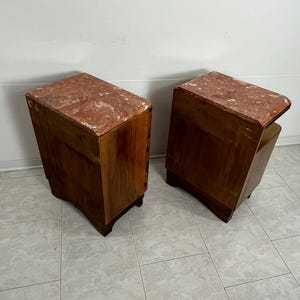 May include: A pair of wooden nightstands with pink marble tops. The nightstands have a simple design with rounded edges and four legs.