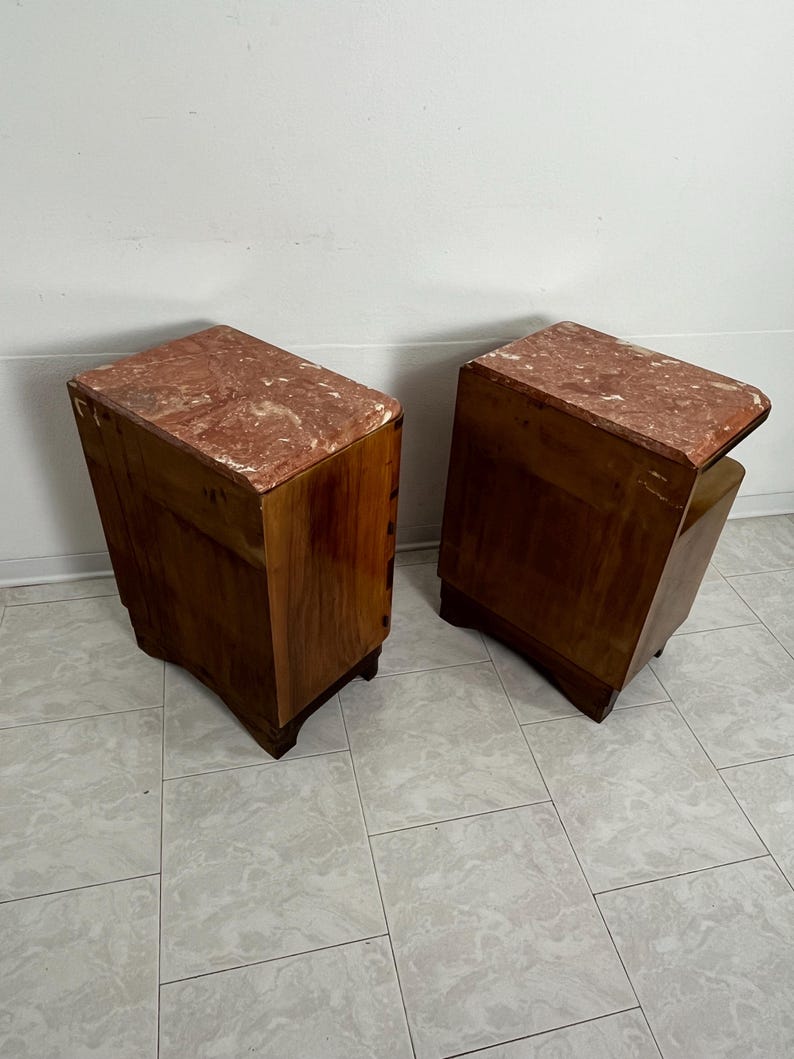 May include: A pair of wooden nightstands with pink marble tops. The nightstands have a simple design with rounded edges and four legs.