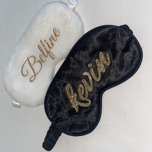Peut inclure: Deux masques de sommeil, un blanc et moelleux avec le nom "Bellina" en lettres dorées pailletées, et un noir satiné avec le nom "Kevin" en lettres dorées pailletées.