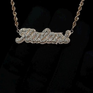 May include: A gold chain necklace with a diamond-encrusted pendant spelling out the name "Julia".