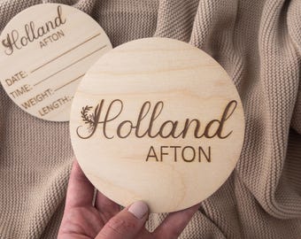 May include: Two round wooden plaques with the name "Holland Afton" engraved on them. One plaque has a space for a date, time, weight, and length.
