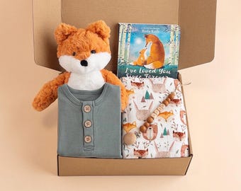 May include: A gift box with a plush orange fox toy, a sage green button-down shirt, a book titled "I've Loved You Since Forever", and a patterned blanket with foxes and bears. A wooden bead teether is also included.