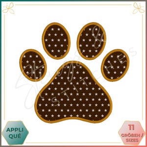 Può includere: Un'impronta di zampa marrone con stelle bianche all'interno, bordata d'oro. L'impronta di zampa è un disegno di ricamo digitale.