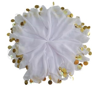 May include: A white, circular scarf with a layered design. The edges are decorated with numerous gold-coloured, circular sequins. The scarf is made of a lightweight fabric, and the sequins are evenly spaced around the perimeter.
