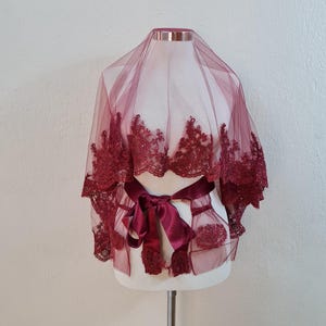 Może przedstawiać: Burgundowy welon z tiulu z koronkową lamówką i dopasowaną wstążką satynową zawiązaną w talii.