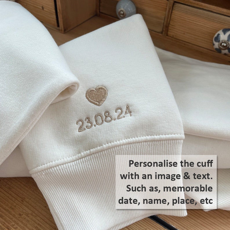 Customisation - A n image of a heart with a date beneath it added  to the sleeve, choose from a selection of thread colours add further personalisation by adding a name or memorable location.