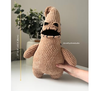 Könnte beinhalten: Ein plüschiger, hellbrauner Oogie Boogie-Puppe, 43 cm hoch und 28 cm breit. Die Puppe hat einen genähten schwarzen Mund und Augen, mit einem abgerundeten Kopf und Armen. Der Artikel ist handgefertigt.