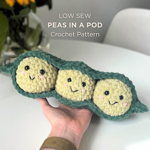 May include: A handmade crochet pea pod with three smiling peas. The peas are light yellow with black eyes and pink cheeks, nestled in a green pod. The text "LOW SEW PEAS IN A POD Crochet Pattern" is visible.