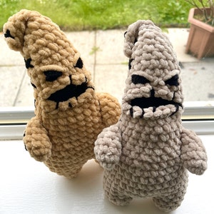 May include: Two crocheted plush toys shaped like the character Oogie Boogie from the movie The Nightmare Before Christmas. One is tan and the other is gray.