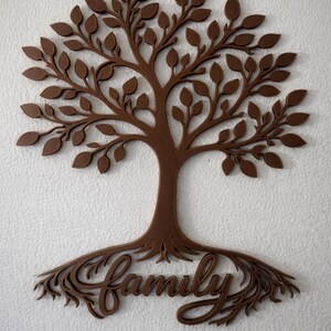 Puede incluir: Adorno de pared de madera marr&oacute;n con forma de &aacute;rbol. El &aacute;rbol tiene un tronco, ramas con hojas y ra&iacute;ces que forman la palabra "Family". Montado en una pared blanca texturizada, ideal para la decoraci&oacute;n del hogar.