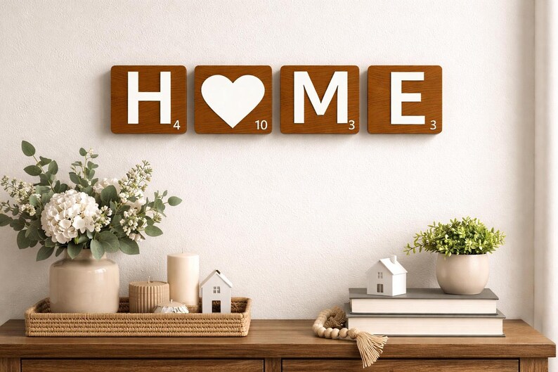 Four brown Scrabble tiles spell "HOME" on a white wall above a wooden console table with decor.