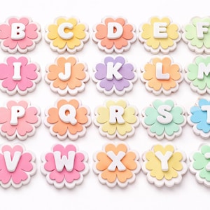 May include: A collection of colorful alphabet letters, each shaped like a flower. The letters are white, set against pastel backgrounds of pink, yellow, orange, green, and purple. The letters are arranged in rows and columns.