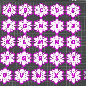 May include: A grid of white flower-shaped designs, each with a letter of the alphabet in the center. The letters are in a bold, sans-serif font and are colored in a bright pink. The flowers have a pink outline.