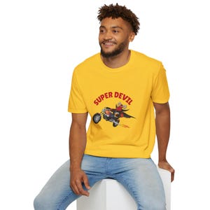 May include: A yellow t-shirt with a red graphic of a devil riding a motorcycle with the text "SUPER DEVIL" above the image.