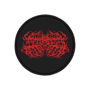 May include: A round, black patch with a red, symmetrical, tribal-style design. The design is intricate and appears to be a stylized emblem or logo. The patch has a black border.