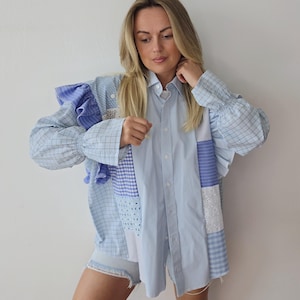 Puede incluir: Una camisa patchwork en tonos azules y blancos, con una mezcla de estampados como rayas y cuadros. Las mangas tienen un diseño con volantes. La camisa se combina con unos shorts vaqueros. La camisa está hecha de varias telas.