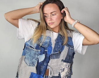 May include: A blue denim vest made from patchwork fabric with a gray knit fabric panel. The vest has a drawstring closure at the waist.